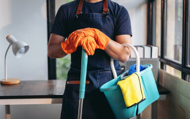 Housekeeping and cleaning concept, Happy young man in orange rubber gloves wiping dust using mop while cleaning on floor at home