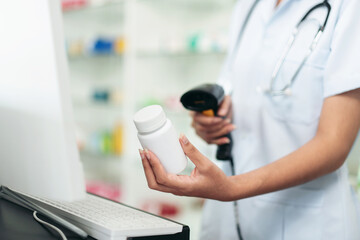 A woman in a white lab coat is holding a bottle of medicine
