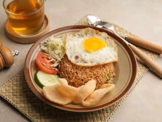 Fried rice with fried egg, vegetable salad and crackers on brown plate