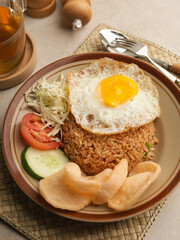 Fried rice with fried egg, vegetable salad and crackers on brown plate
