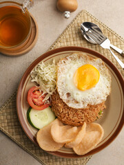 Fried rice with fried egg, vegetable salad and crackers on brown plate
