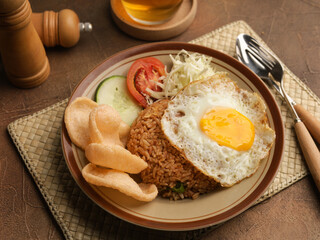 Fried rice with fried egg, vegetable salad and crackers on brown plate