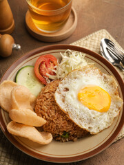 Fried rice with fried egg, vegetable salad and crackers on brown plate