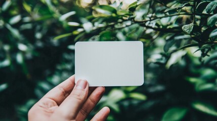 A hand displays a blank white card with rounded corners.