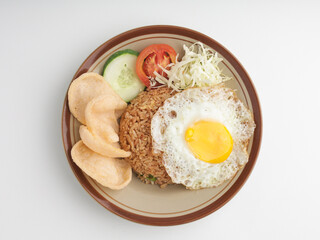 Fried rice with fried egg, vegetable salad and crackers on brown plate