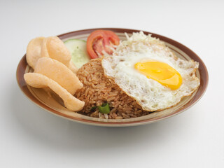 Fried rice with fried egg, vegetable salad and crackers on brown plate