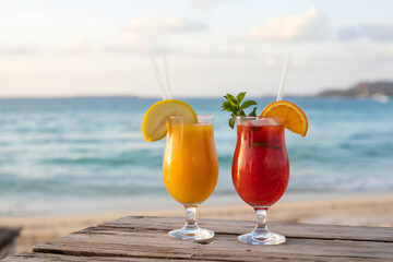 Tropical cocktails with garnishes on weathered wood against blurred ocean