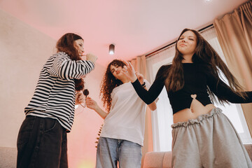 Teenage girls dancing and singing at home party
