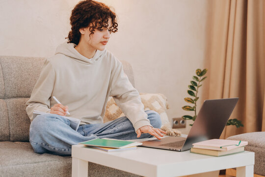 Teen student girl studying at home using laptop and taking notes