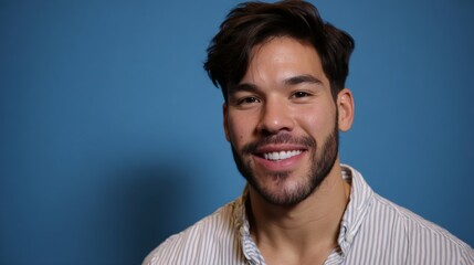 Obraz premium Young hispanic man smiling on blue background, portrait of successful millennial