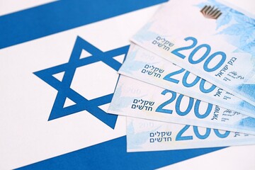 Israel New Shekels banknotes on national flag. The current Israel money bills lies on flag