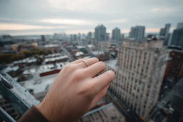 Hand holds ring, gazing out at cityscape, feeling hopeful and romantic
