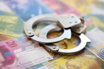 Swiss franc banknotes and handcuffs. The current francs money bills and cuffs lies on table