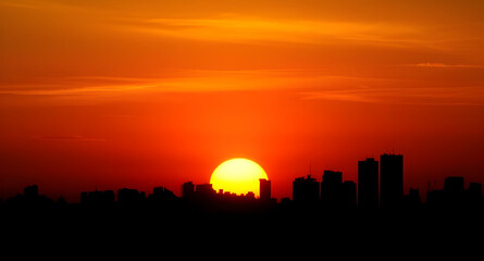 Naklejka premium City at sunset, Urban sunset scene, Sunset over city, City skyline sunset, Cityscape at dusk, Golden hour city, Sunset buildings, Evening city lights, Sunset horizon city, City during twilight, Glowin