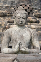Closeup front view of ancient Vairocana buddha statue in dharmachakra mudra, Borobudur stupa, Magelang, Central Java, Indonesia