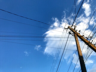 Power lines stretch across a bright blue sky with clouds