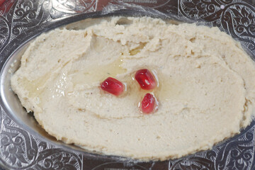 Creamy hummus topped with pomegranate seeds in a dish