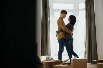 Happy couple embracing in new home with moving boxes