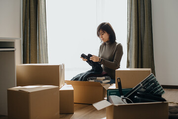 Woman packing clothes into cardboard boxes while moving house