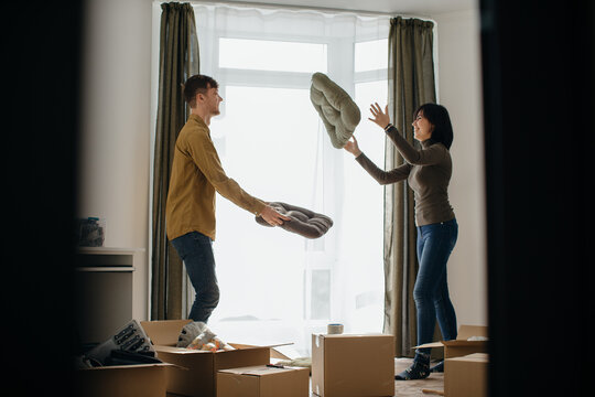 Happy couple playing with cushions while moving into new home - Powered by Adobe