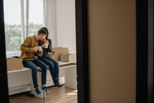 Young couple taking break while moving into new apartment eating and drinking