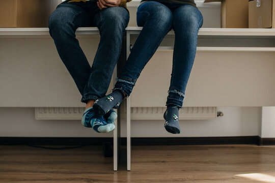 Couple wearing jeans and colorful socks taking a break during moving day