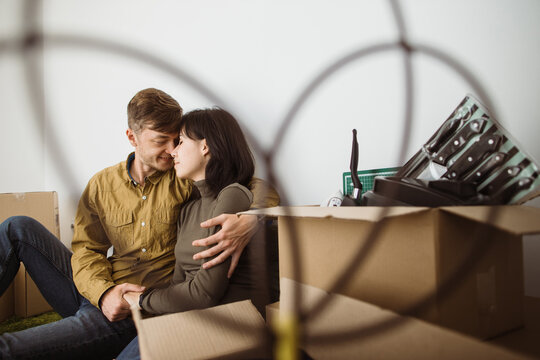 Young couple resting and embracing while moving into new home