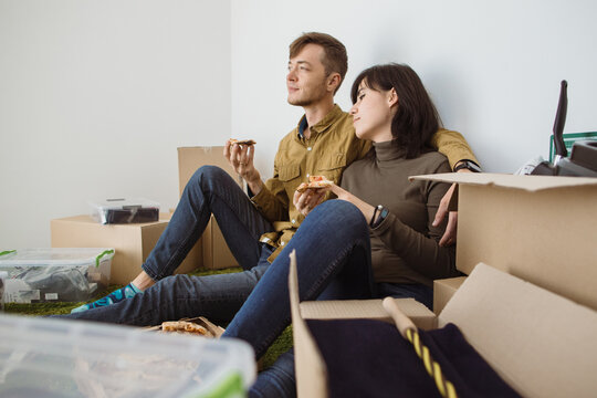 Young couple eating pizza and resting during move into new home - Powered by Adobe