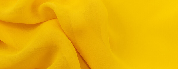 Yellow Silk, satin fabric texture with folds and waves. Textile. Material. Fashion