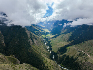 An aerial view capturing a winding river carving its way through a verdant mountain valley, flanked...