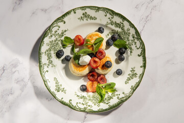 Delicious breakfast cheesecakes decorated with fresh berries and mint on a beautiful vintage plate