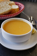 Warm bowl of butternut squash soup with bread basket