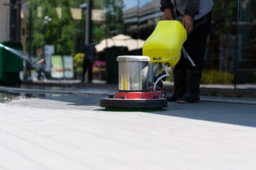 Workers are cleaning the road with a floor scrubber