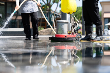 Workers are cleaning the road with a floor scrubber