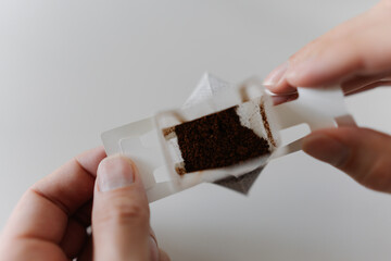Top view of male hands carefully placing drip coffee bag into transparent glass cup, getting ready...