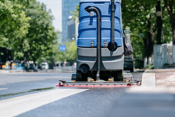Workers are cleaning the road with a floor scrubber