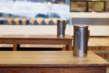 Metal or steel water jar arranged in a row in the restaurant on the wooden table