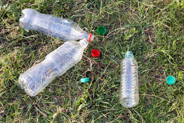 Plastic water bottles thrown on the green field, plastic pollution. Climate change issues with the...