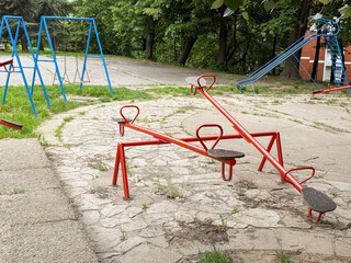 Colorful seesaws and swings in an empty outdoor playground. A quiet urban space for children's play and recreation.