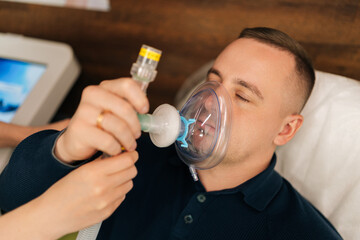 Close-up of medical professional providing oxygen mask during respiratory therapy to male patient, enhancing breathing techniques and lung function. Training increases body adaptation abilities.