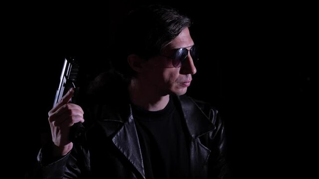 mid-shot captures a cool and mysterious mood as a man in a leather jacket and sunglasses holds a handgun, illuminated by a single light source against a dark background, suggesting a dramatic scenario