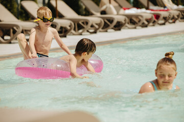Children playing with inflatable ring in swimming pool at water park