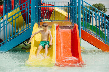 Child sliding down into waterpark pool on colorful slide