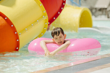 Child having fun with pink inflatable ring at water park