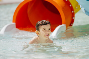 Happy child smiling and playing in water park pool