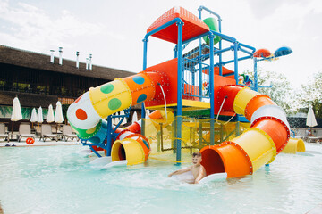 Child having fun sliding in colorful water park playground