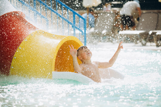 Child having fun going down water slide in aqua park pool