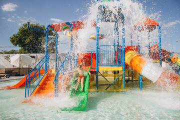 Child sliding down into waterpark pool on sunny day