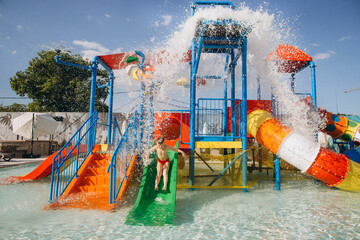 Child sliding down into waterpark pool on sunny day