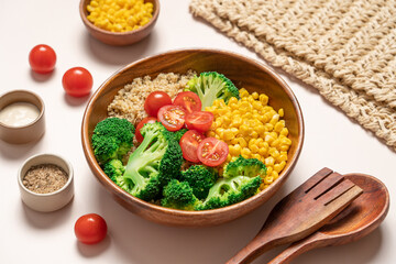 Broccoli, corn, quinoa, tomato salad in wooden bowl on light beige background. Healthy food concept